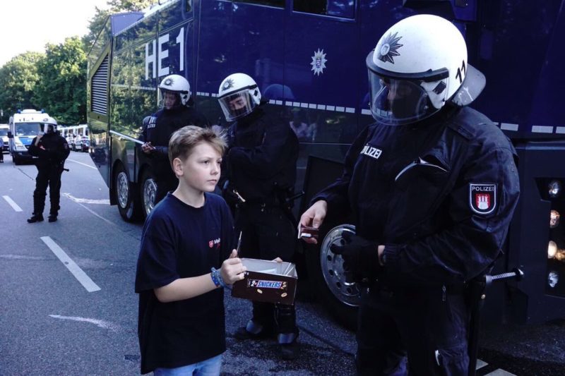 Junge verteilt Pausenriegel an Polizeibeamte